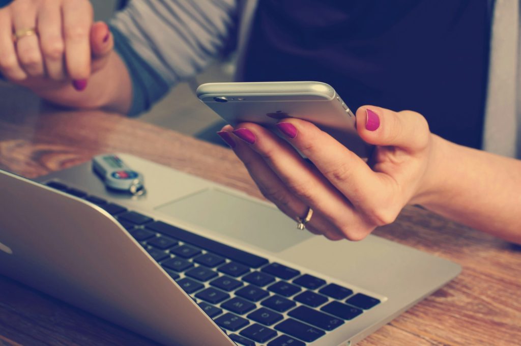 Woman using phone and laptop simultaneously